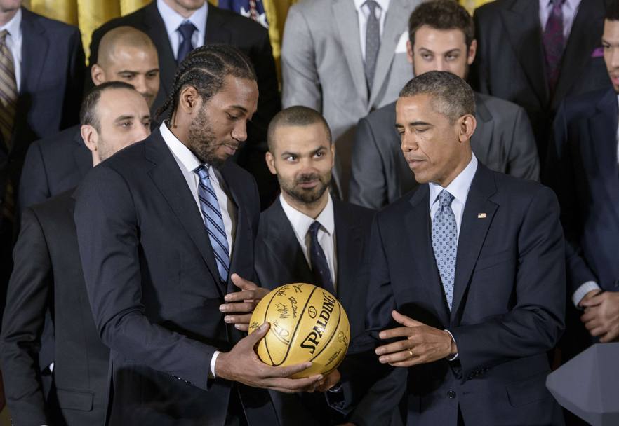 Obama ricevi il pallone autografato dalle gigantesche mani di Kawhi Leonard. Afp